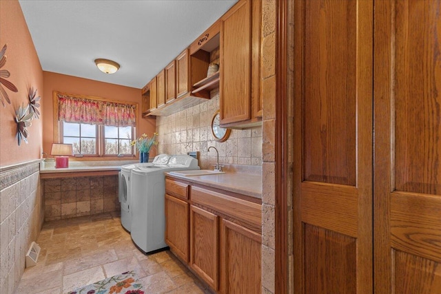 clothes washing area featuring cabinets, sink, and washing machine and dryer