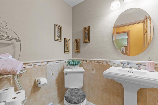 bathroom with toilet, tile walls, and sink