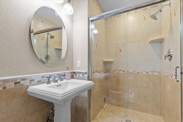 bathroom with tile walls, a shower with door, and sink