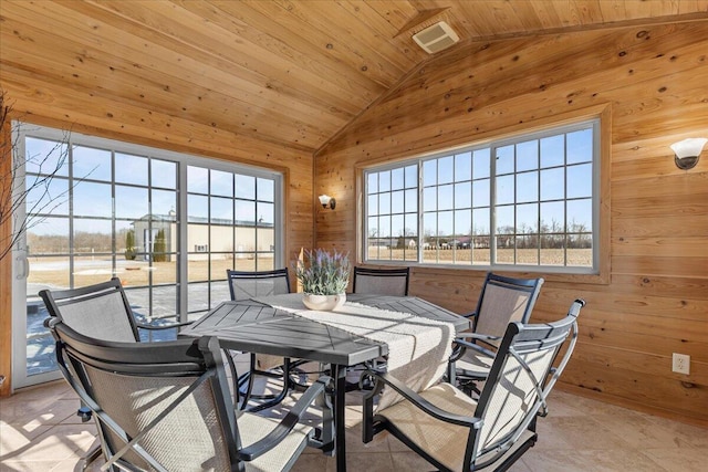 tiled dining room featuring vaulted ceiling, wood ceiling, and wooden walls