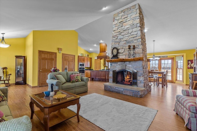 living room with high vaulted ceiling, light wood-type flooring, and a fireplace