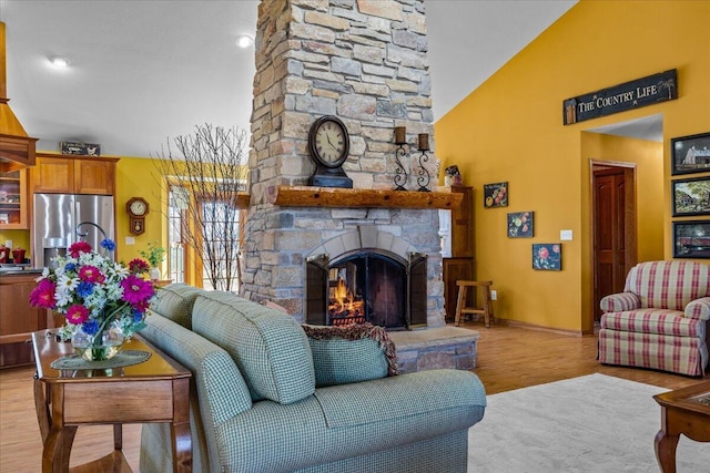 living room with lofted ceiling, light wood-type flooring, and an outdoor stone fireplace