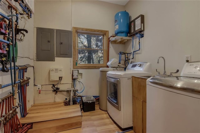 washroom featuring washing machine and dryer, cabinets, electric panel, and light hardwood / wood-style flooring