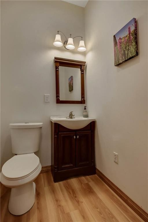 bathroom with toilet, vanity, and wood-type flooring