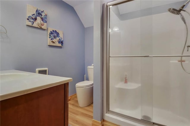 bathroom with toilet, a shower with shower door, lofted ceiling, wood-type flooring, and vanity