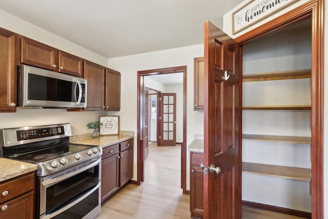 kitchen with light stone counters, light hardwood / wood-style flooring, and stainless steel appliances