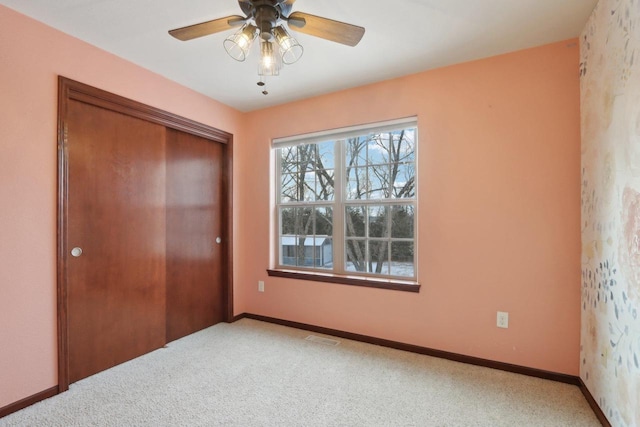 unfurnished bedroom with ceiling fan, a closet, and carpet floors