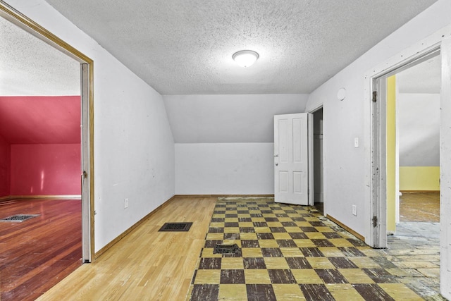 bonus room featuring lofted ceiling and a textured ceiling