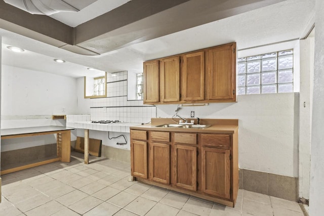 kitchen with light tile patterned floors, backsplash, and sink