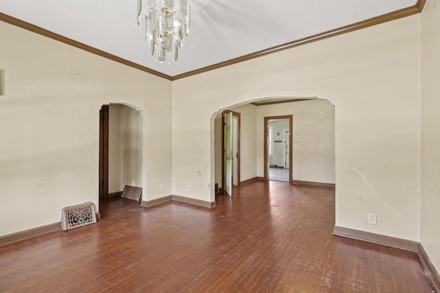 spare room with dark wood-type flooring, ornamental molding, and an inviting chandelier