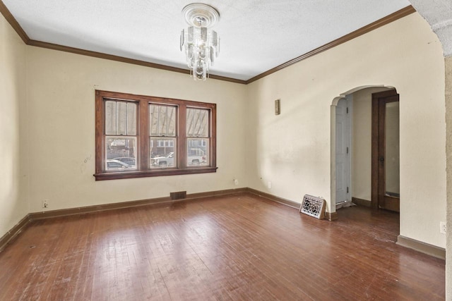 spare room with a textured ceiling, dark wood-type flooring, and crown molding