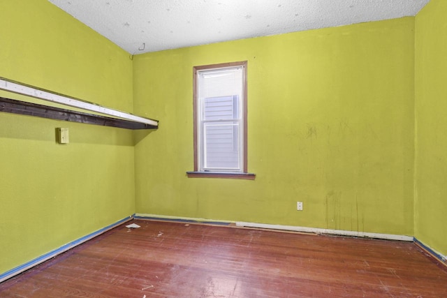 unfurnished room with a textured ceiling and dark wood-type flooring