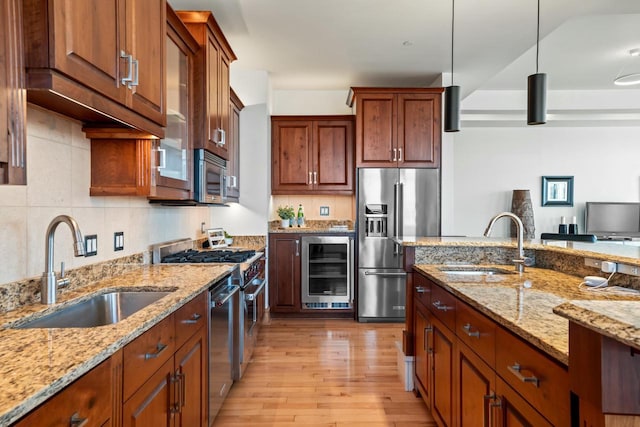 kitchen with high end appliances, decorative light fixtures, beverage cooler, and sink