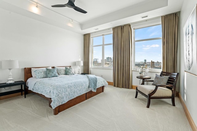 bedroom featuring ceiling fan, light carpet, track lighting, and multiple windows