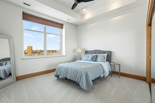 bedroom featuring ceiling fan, rail lighting, light carpet, and a raised ceiling