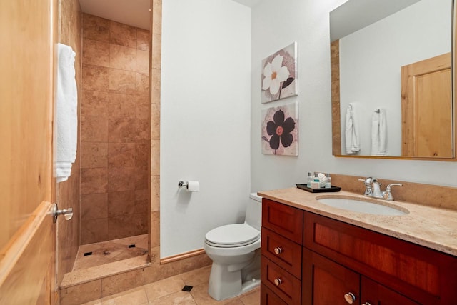 bathroom with toilet, vanity, tile patterned flooring, and tiled shower