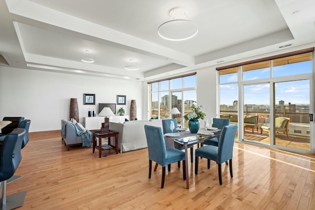 dining area featuring light wood-type flooring and a tray ceiling