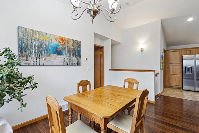 dining space with dark hardwood / wood-style flooring, lofted ceiling, and a chandelier