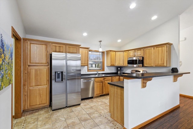 kitchen with kitchen peninsula, stainless steel appliances, vaulted ceiling, a breakfast bar, and sink