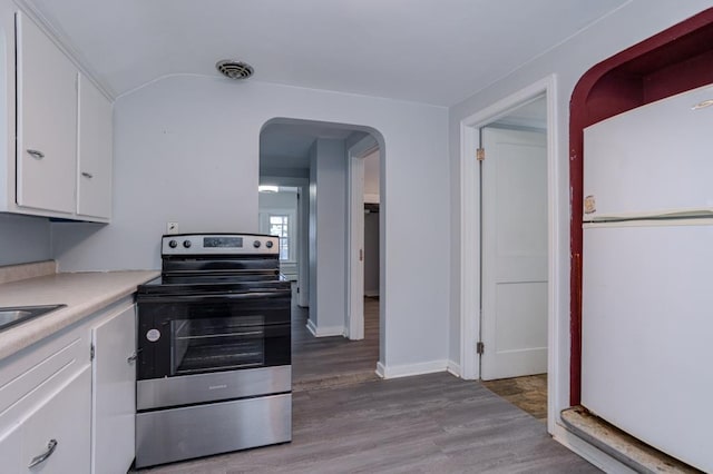 kitchen featuring hardwood / wood-style flooring, white refrigerator, stainless steel electric range oven, and white cabinets