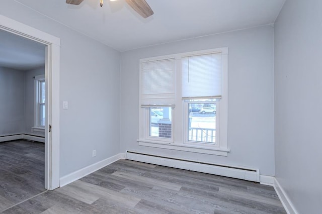 unfurnished room with ceiling fan, a baseboard radiator, and wood-type flooring