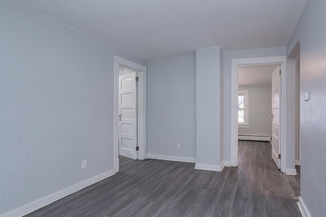 unfurnished room with dark wood-type flooring and baseboard heating