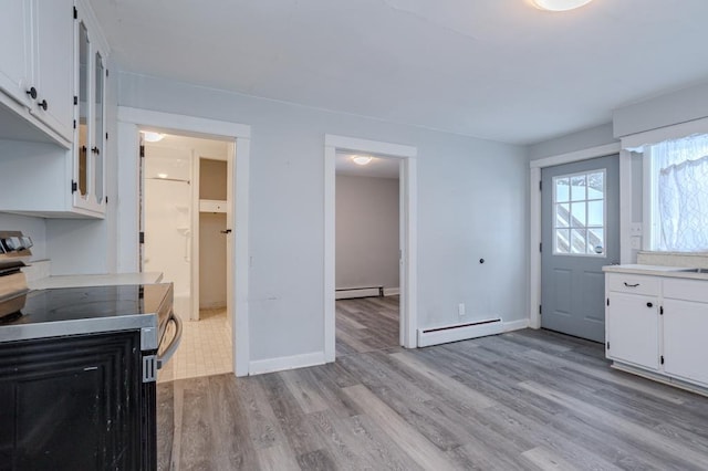 kitchen with baseboard heating, white cabinetry, and light hardwood / wood-style flooring