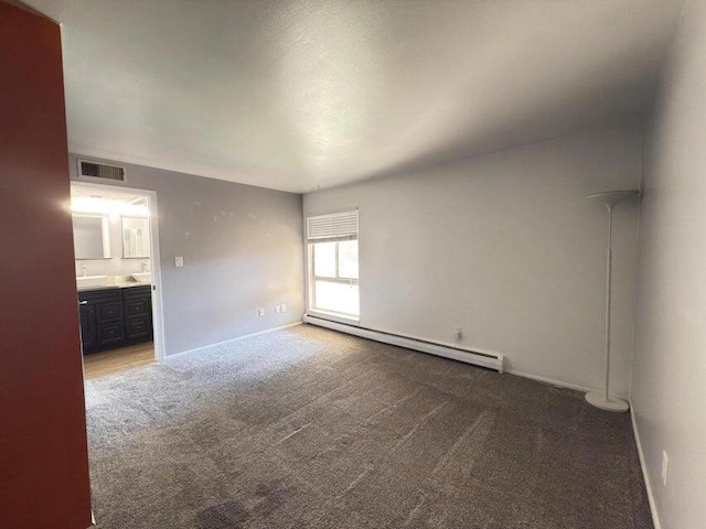 unfurnished bedroom with baseboard heating, ensuite bathroom, and carpet flooring