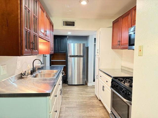 kitchen featuring white cabinets, sink, stainless steel appliances, and light hardwood / wood-style floors