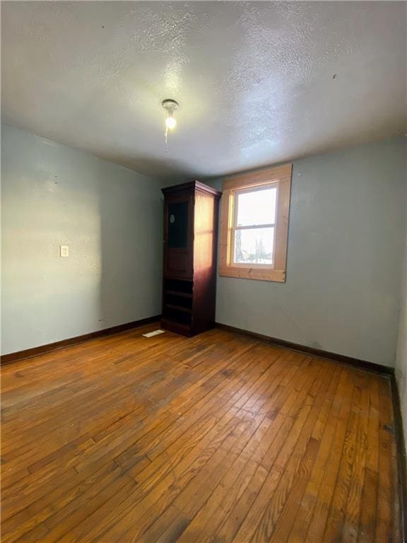 empty room with wood-type flooring and a textured ceiling