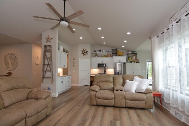 living room featuring vaulted ceiling, ceiling fan, and light hardwood / wood-style floors