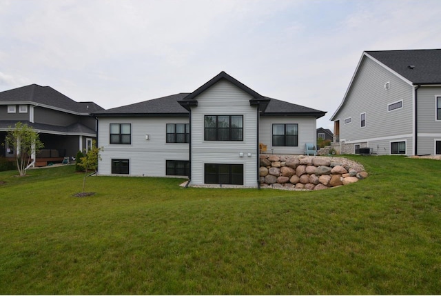 rear view of property featuring central AC unit and a lawn