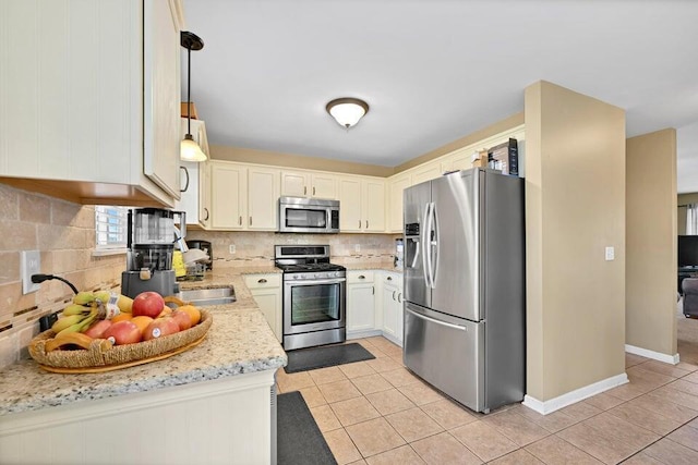 kitchen featuring light tile patterned floors, appliances with stainless steel finishes, backsplash, light stone countertops, and pendant lighting