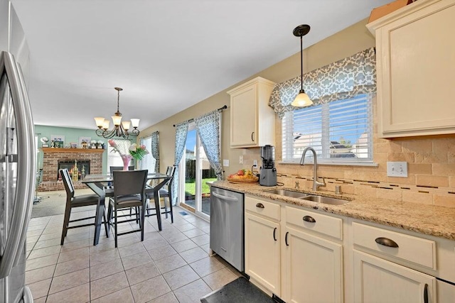 kitchen featuring sink, hanging light fixtures, stainless steel appliances, and cream cabinetry