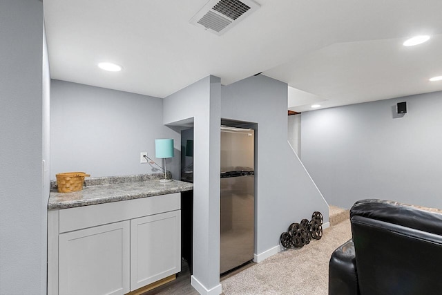 bar featuring white cabinets and light carpet