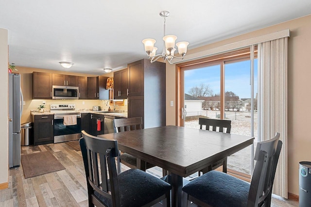 dining room featuring an inviting chandelier, light hardwood / wood-style floors, and sink