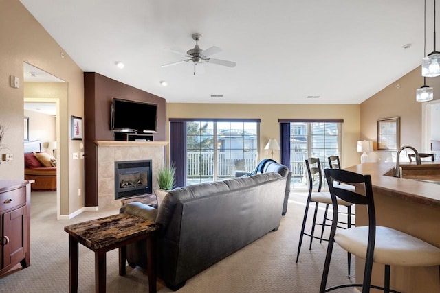 carpeted living room featuring lofted ceiling, ceiling fan, sink, and a tile fireplace