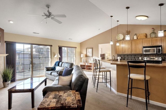 carpeted living room with ceiling fan and vaulted ceiling