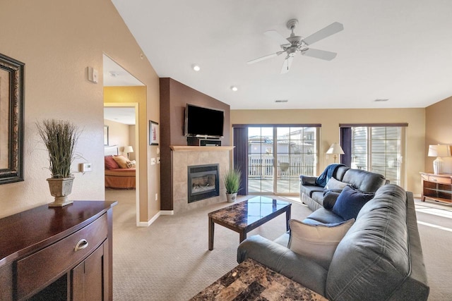 carpeted living room with ceiling fan, lofted ceiling, and a tiled fireplace