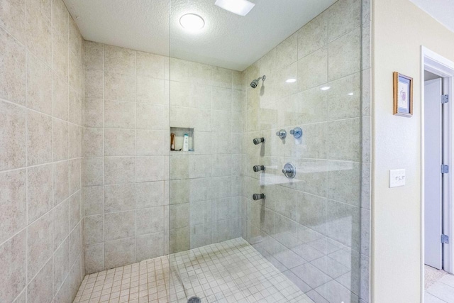 bathroom with a textured ceiling, a tile shower, and tile patterned flooring