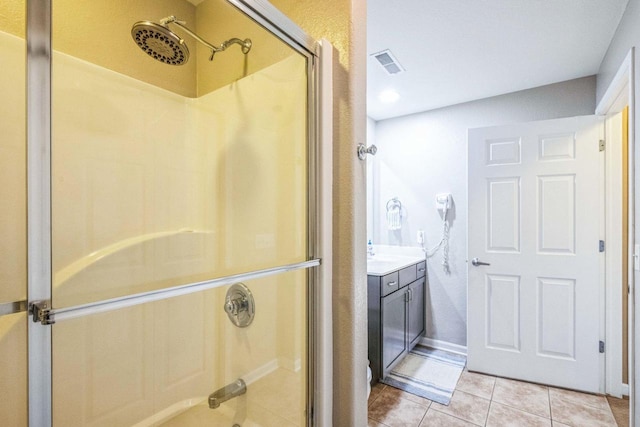 bathroom with a shower with shower door, vanity, and tile patterned floors