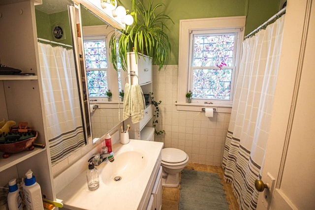 bathroom featuring toilet, a healthy amount of sunlight, tile walls, and vanity