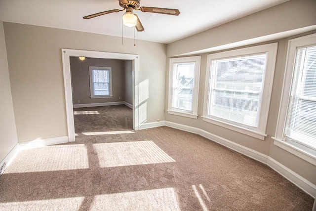 carpeted spare room featuring ceiling fan and plenty of natural light