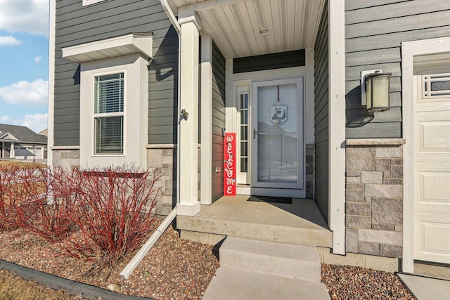 doorway to property featuring a garage and stone siding