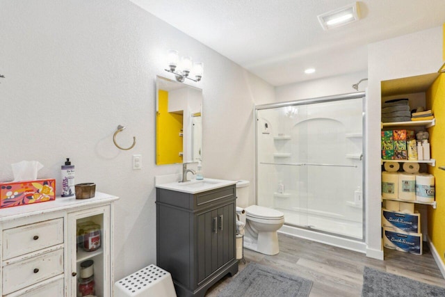 bathroom with a shower with shower door, hardwood / wood-style flooring, vanity, and toilet