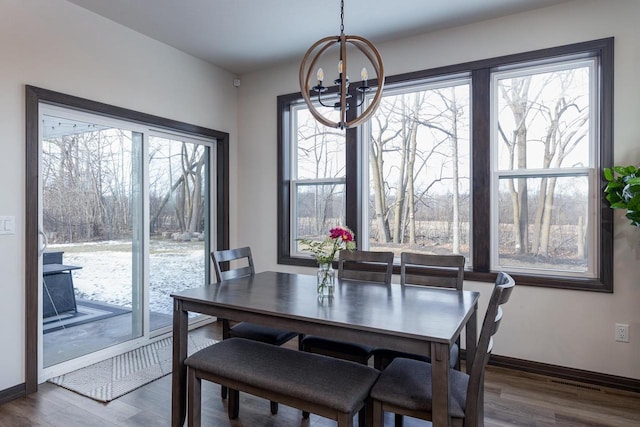 dining area with a healthy amount of sunlight, wood-type flooring, and a notable chandelier