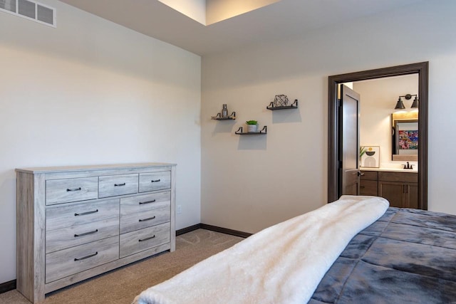 bedroom featuring ensuite bathroom, light colored carpet, and sink