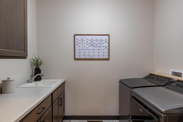 laundry area with sink, washing machine and clothes dryer, and cabinets