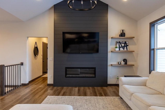 living room featuring wood-type flooring, lofted ceiling, and a large fireplace