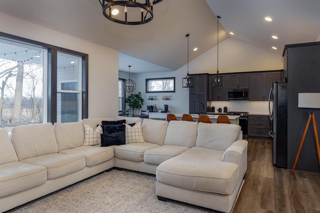 living room with a wealth of natural light, lofted ceiling, a chandelier, and hardwood / wood-style flooring